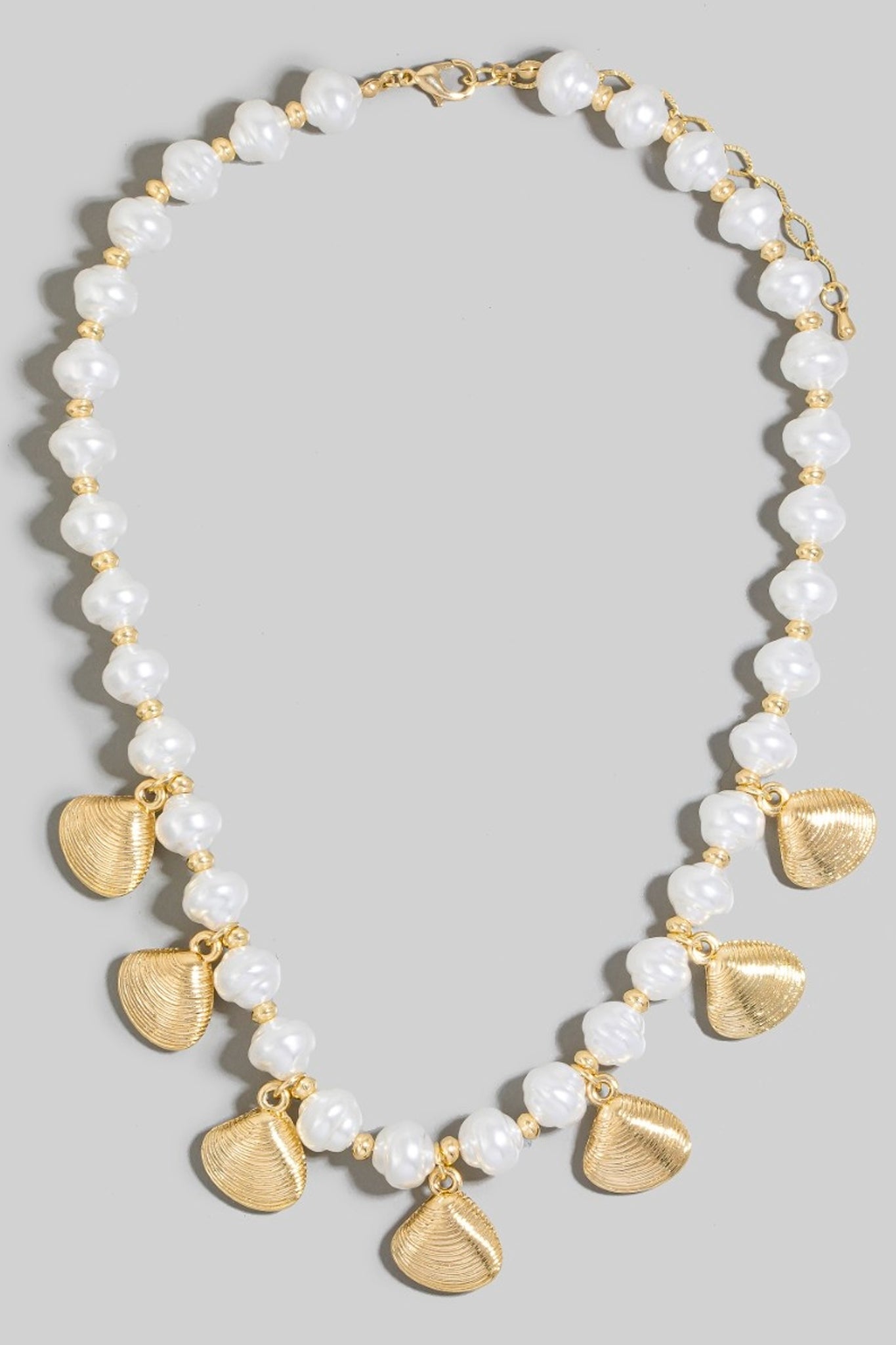 Larrea Cove's pearl clam shell charm necklace exudes coastal elegance, perfect for accessorizing boho dresses and beach cover-ups.