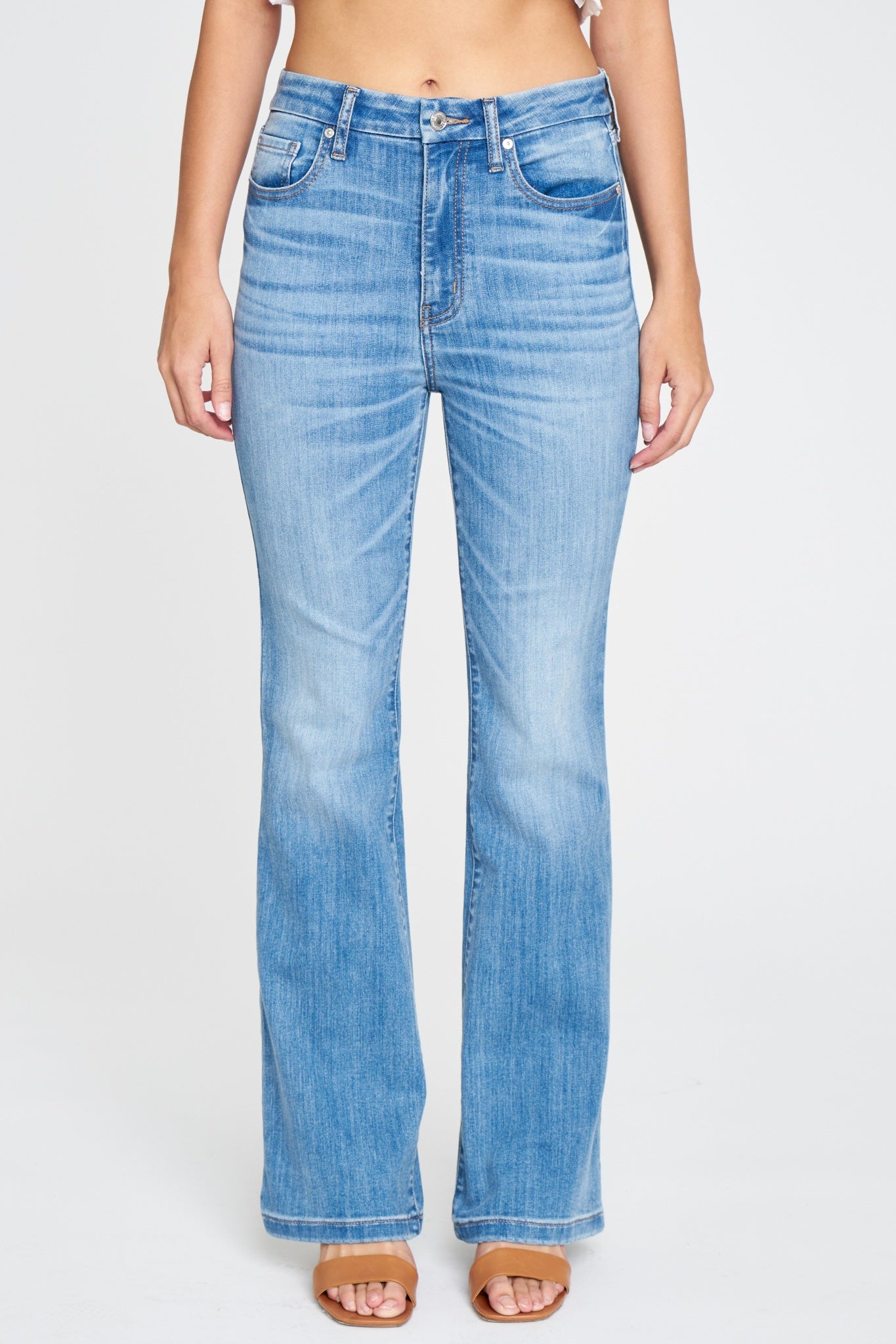 Eunina Aliyah Super High Rise Flare Jeans in Verbena, featuring a medium wash with fading and whiskering, a super high-rise design, and a flared inseam. The model is styled in a relaxed fit, showcasing the classic five-pocket design and belt loops, paired with sunglasses.