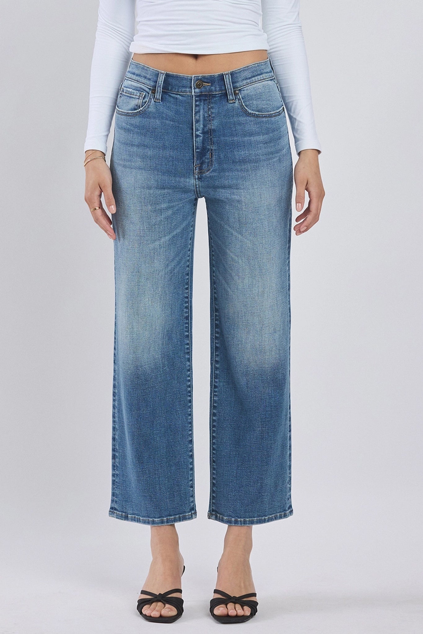 Eunina Dawn super high rise wide leg cropped jeans in Aliso, showcasing medium wash denim with fading and whiskering details. The jeans feature a clean hem, five-pocket design, belt loops, and a hidden zip fly button closure. The model is wearing sunglasses, highlighting the casual yet stylish look. The jeans have an 11.5-inch high rise and a 26.5-inch cropped inseam.