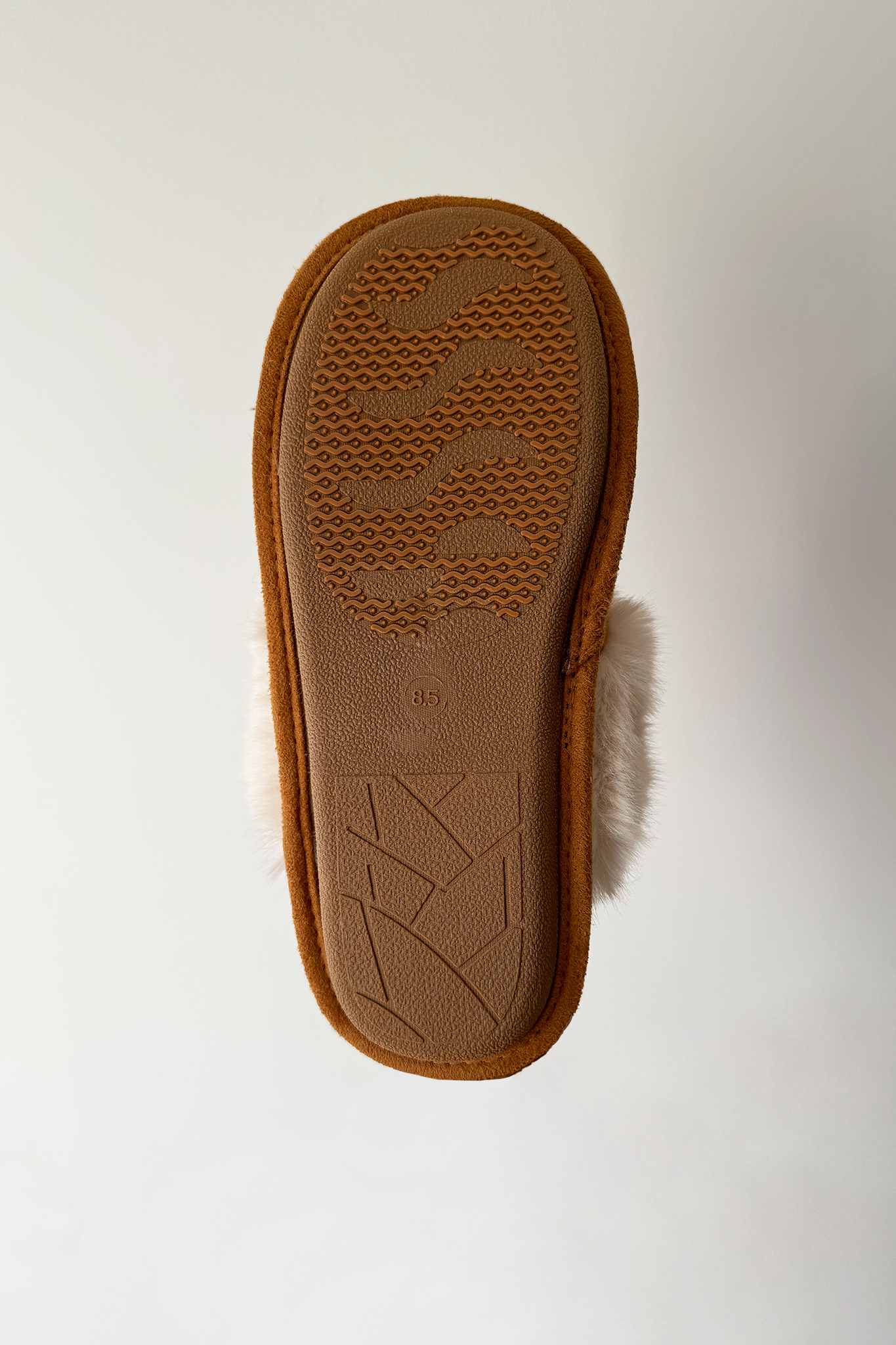 A pair of cozy faux fur slippers in a soft color, featuring a plush design that wraps around the foot for comfort. The slippers have a simple, stylish appearance suitable for indoor wear.