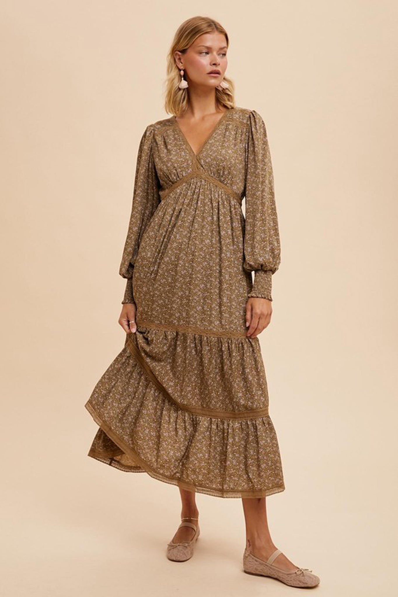 A floral maxi dress by Larrea Cove featuring lace trim, perfect for fall 2024. The dress is elegant and flowy, showcasing a vibrant floral pattern. Accompanying the dress are stylish sunglasses, enhancing the overall fashionable look.