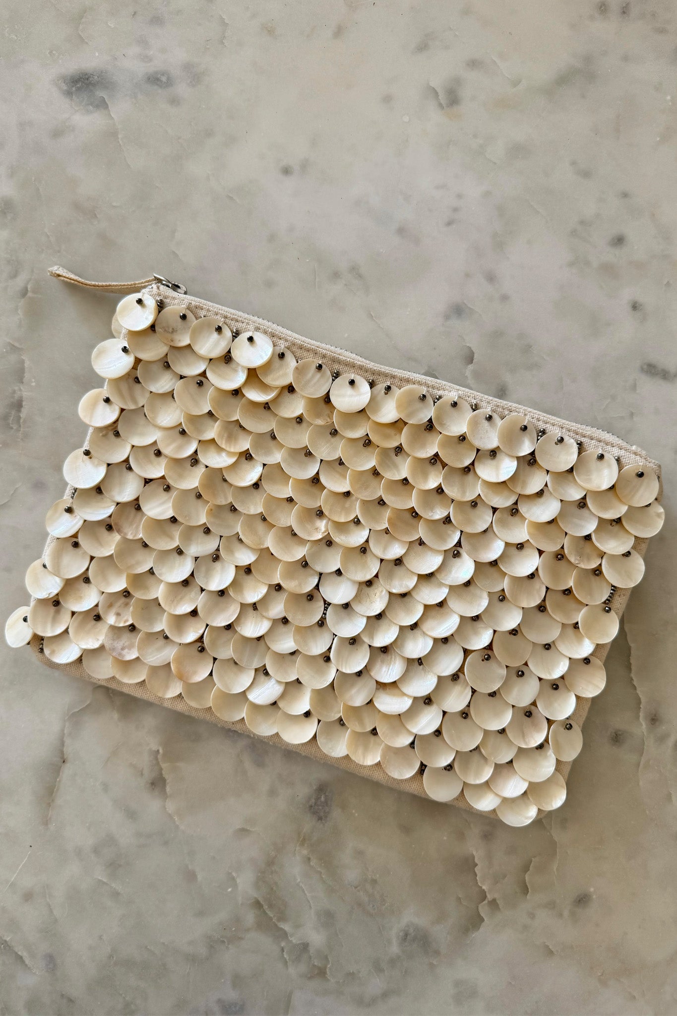 A stylish handbag crafted from mother of pearl shell discs, designed by ANTIK KRAFT. The handbag features a chic and iridescent surface, perfect for summer fashion. It is accompanied by sunglasses, enhancing its trendy appeal. The product is categorized under Handbags in the Apparel & Accessories section.