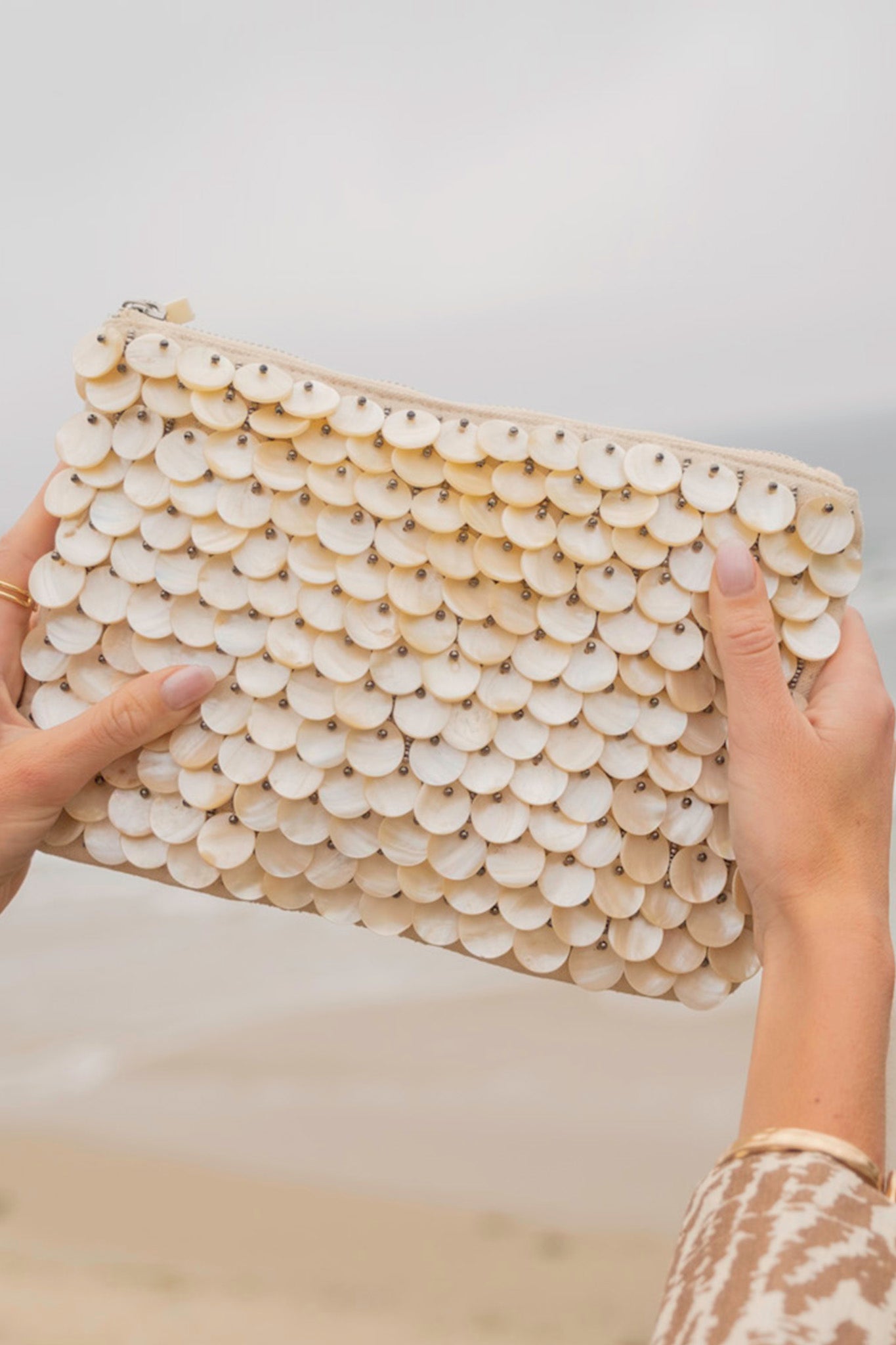 Alt text: A stylish Mother of Pearl Shell Discs Handbag by ANTIK KRAFT, featuring shimmering shell discs that create a beachy, sophisticated look. The handbag is compact yet spacious, ideal for both beach outings and evening events. It is displayed against a neutral background, highlighting its unique and natural design.