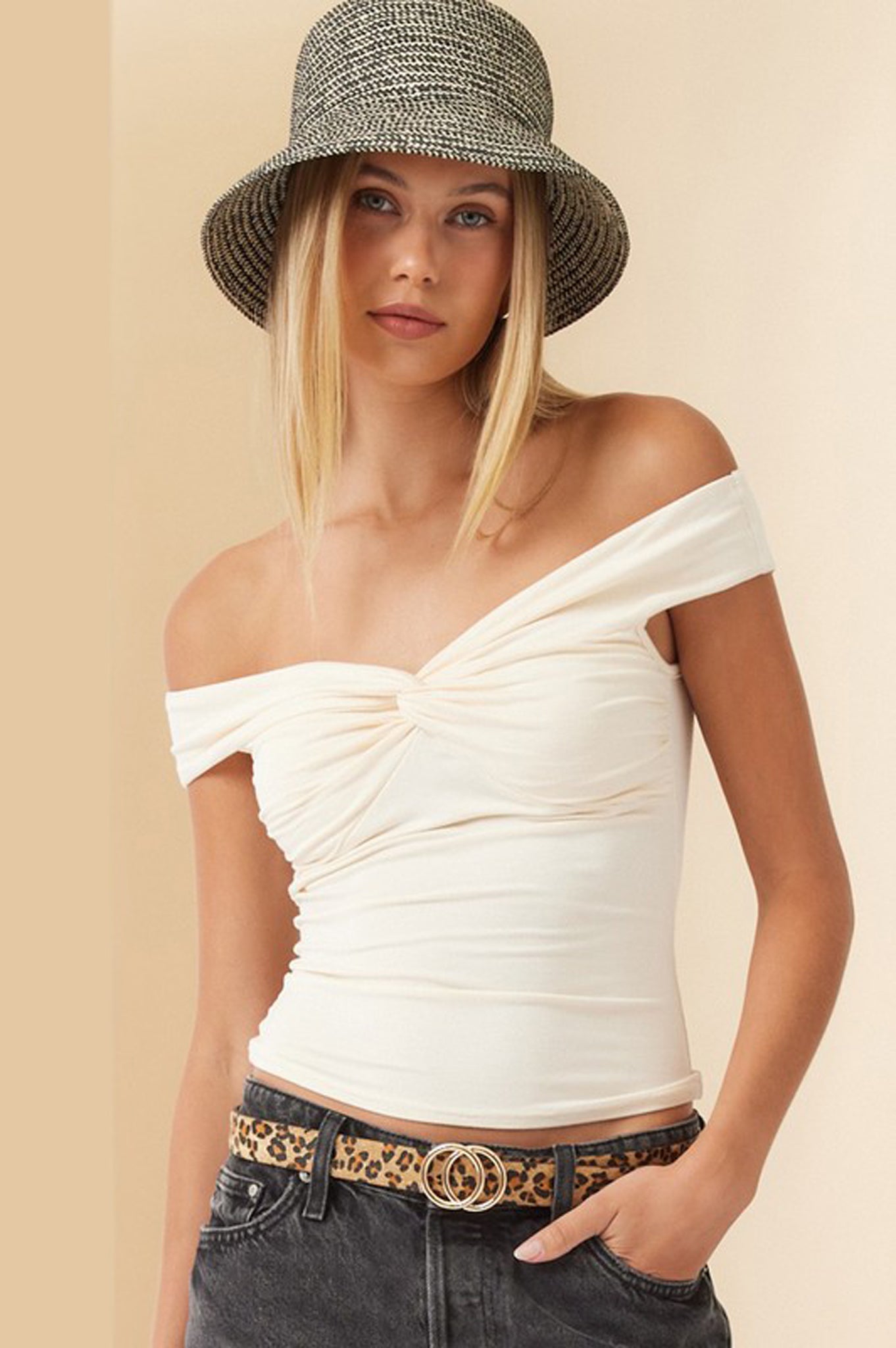 Off-shoulder cream top by Larrea Cove displayed on a mannequin or hanger. The top features a relaxed fit and flowing sleeves, ideal for a casual yet stylish look. Accompanying the top are a pair of trendy sunglasses placed nearby, enhancing the outfit's summer vibe.