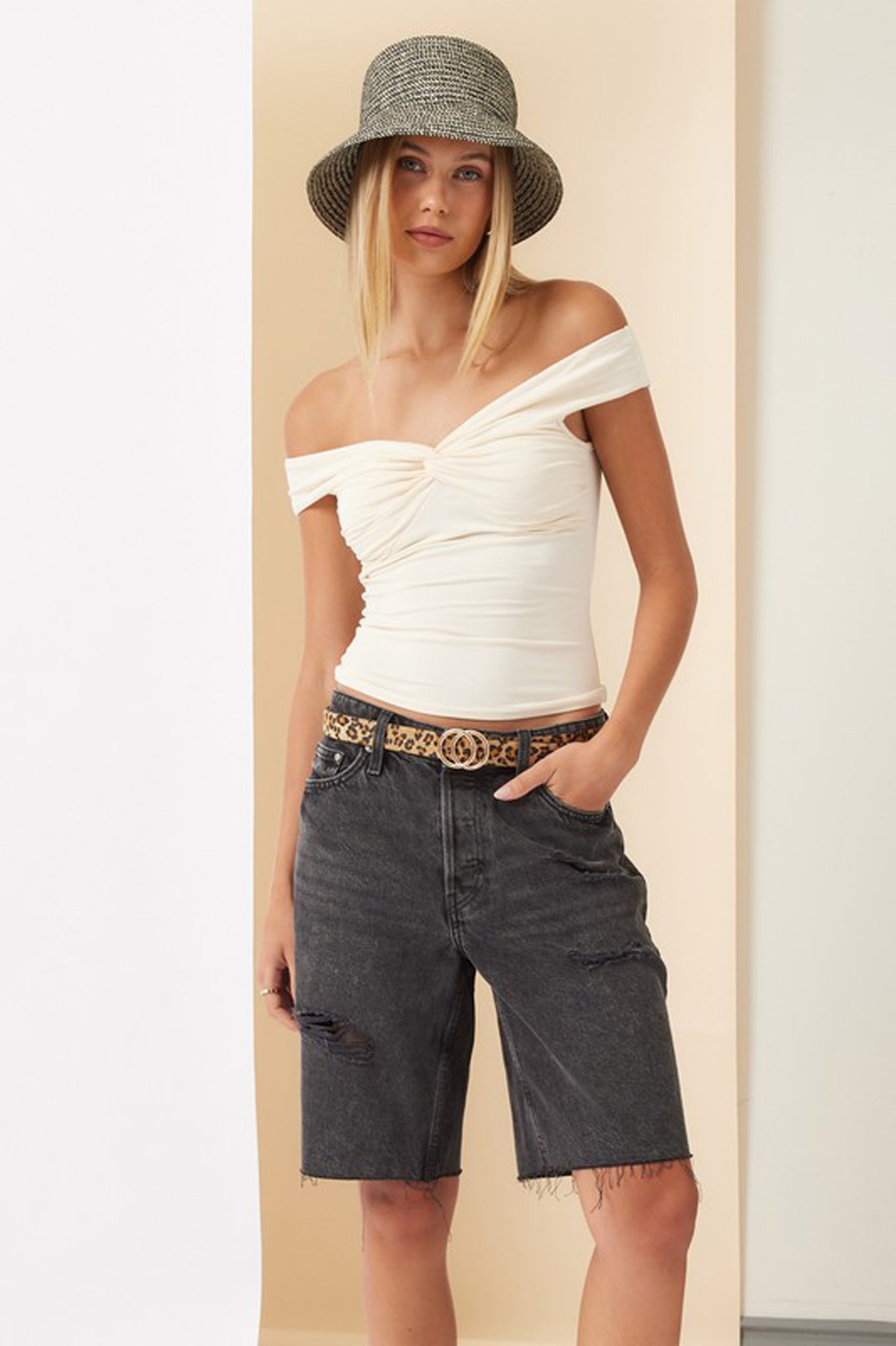 A cream-colored off-shoulder top from Larrea Cove, featuring a relaxed fit and short sleeves. The top is styled for a fall 2024 collection, with a modern and trendy look suitable for various occasions. The image highlights the fabric's texture and color, perfect for layering in cooler weather.