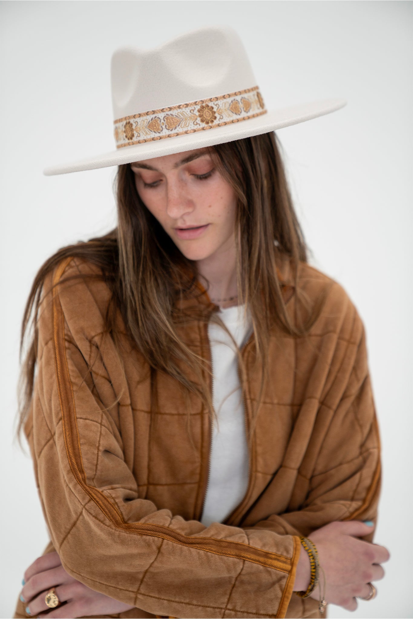 A stylish ivory hat with a round brim and a dipped crown, featuring a patterned ribbon around the crown for a bohemian touch. The hat is designed for sun protection and outdoor adventures.
