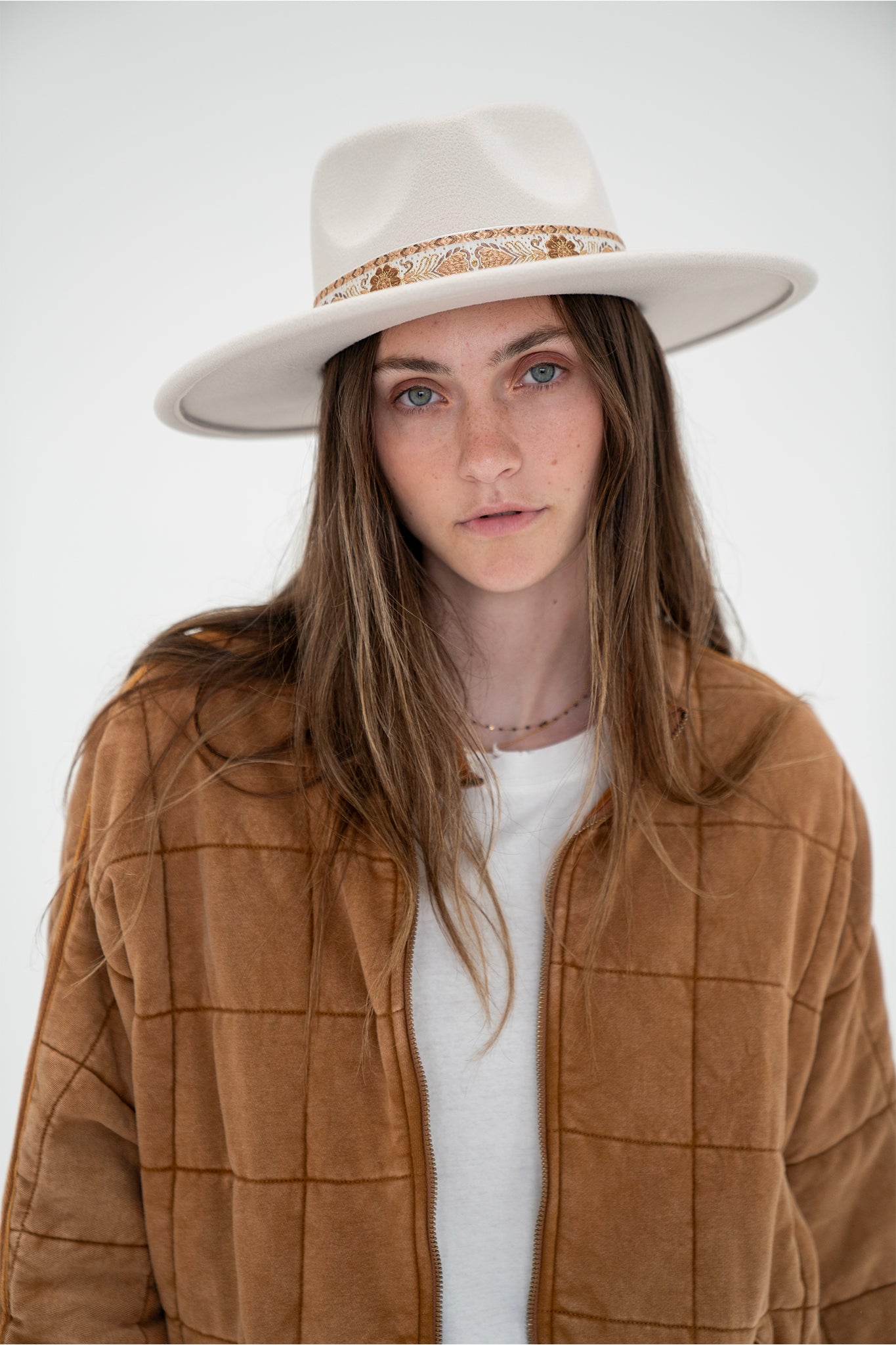 A stylish Soloman Pattern Stripe Hat in ivory by Larrea Cove, featuring a textured stripe design. The hat is paired with sunglasses, showcasing a trendy accessory combination. Ideal for sun protection and fashion-forward looks.