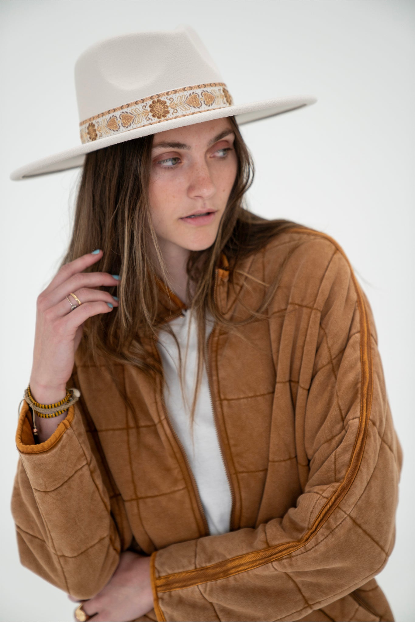 A stylish Soloman Pattern Stripe Hat in ivory, designed by Larrea Cove. The hat features a striped pattern and is suitable for casual wear. It is displayed alongside sunglasses, emphasizing its summer accessory appeal.