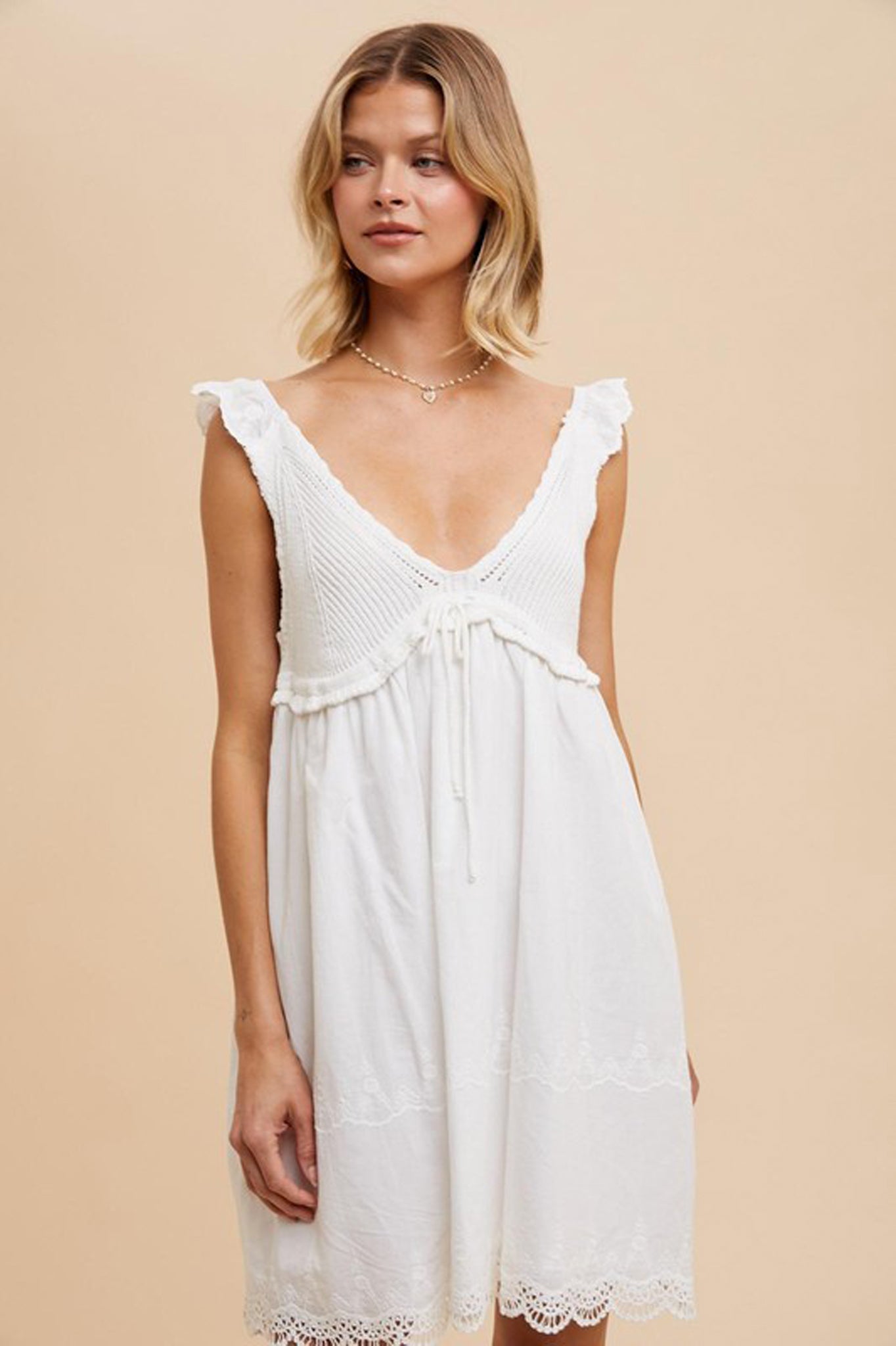 A V-neck crochet mini dress by Larrea Cove, featuring intricate crochet detailing and a flattering silhouette. The dress is styled with sunglasses, suggesting a chic summer look. The color is Poppi Seed, reflecting a trendy and vibrant aesthetic. Ideal for casual or semi-formal occasions, this dress represents the latest fashion trends for July 2024.