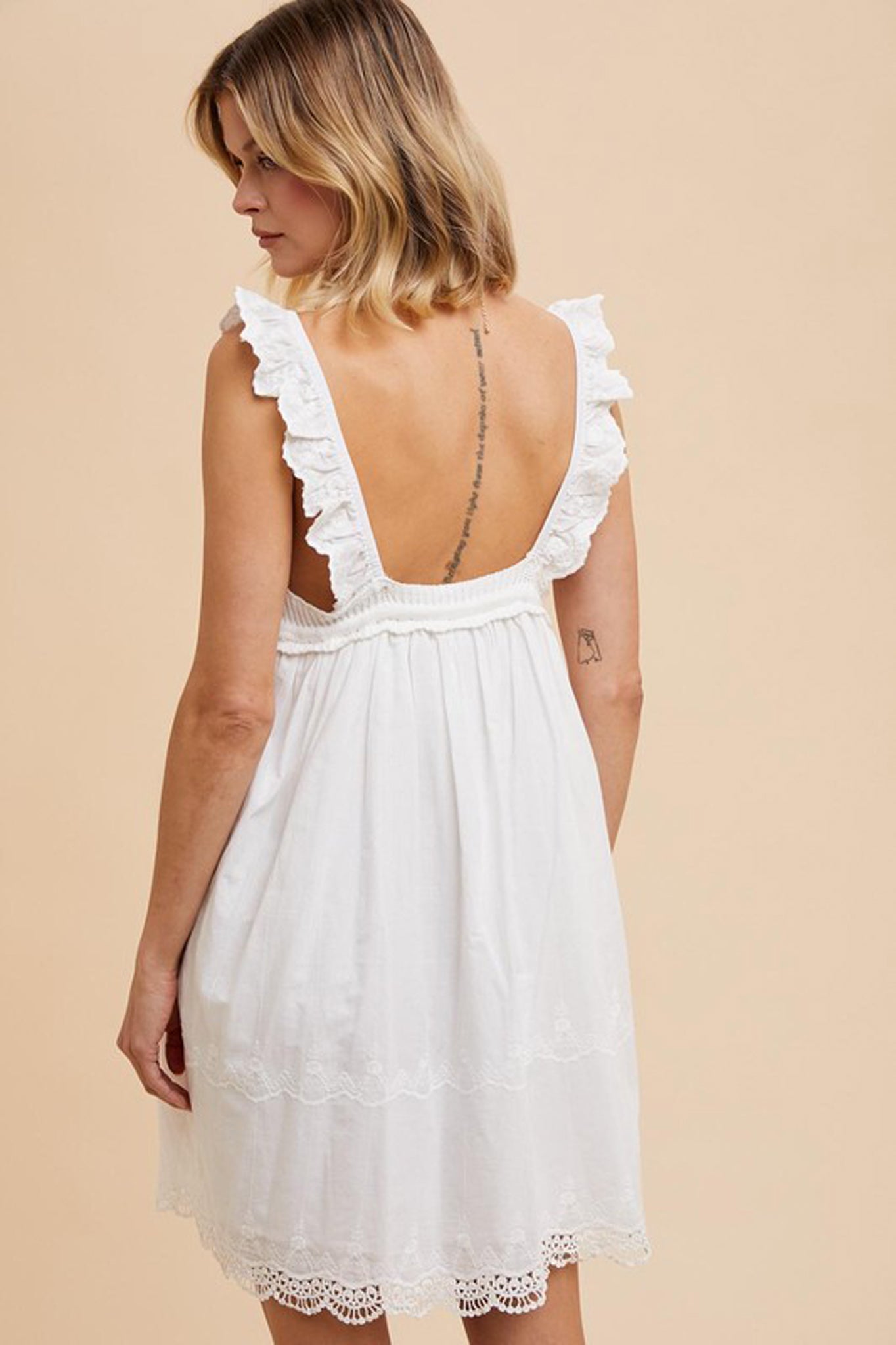 V-Neck Crochet Mini Dress by Larrea Cove in a light color, featuring a crochet design and a flattering V-neckline. The dress is styled with sunglasses, set against a neutral background. Ideal for summer outings.