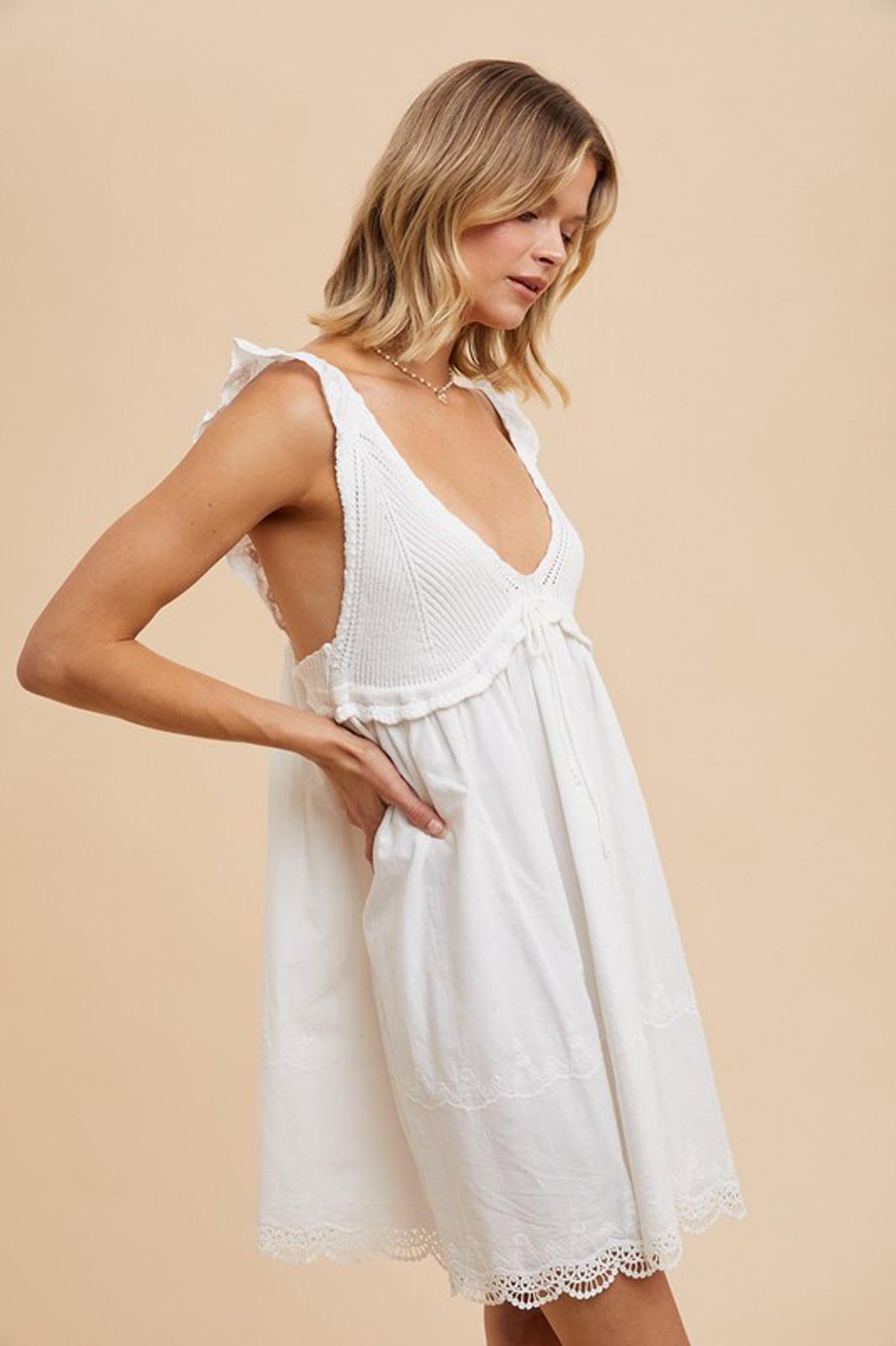 A V-neck crochet mini dress by Larrea Cove, featuring a delicate crochet pattern and a stylish design suitable for summer wear. The dress has a playful and feminine silhouette, perfect for casual outings or beach days. Accompanying the dress are stylish sunglasses, enhancing the trendy look.