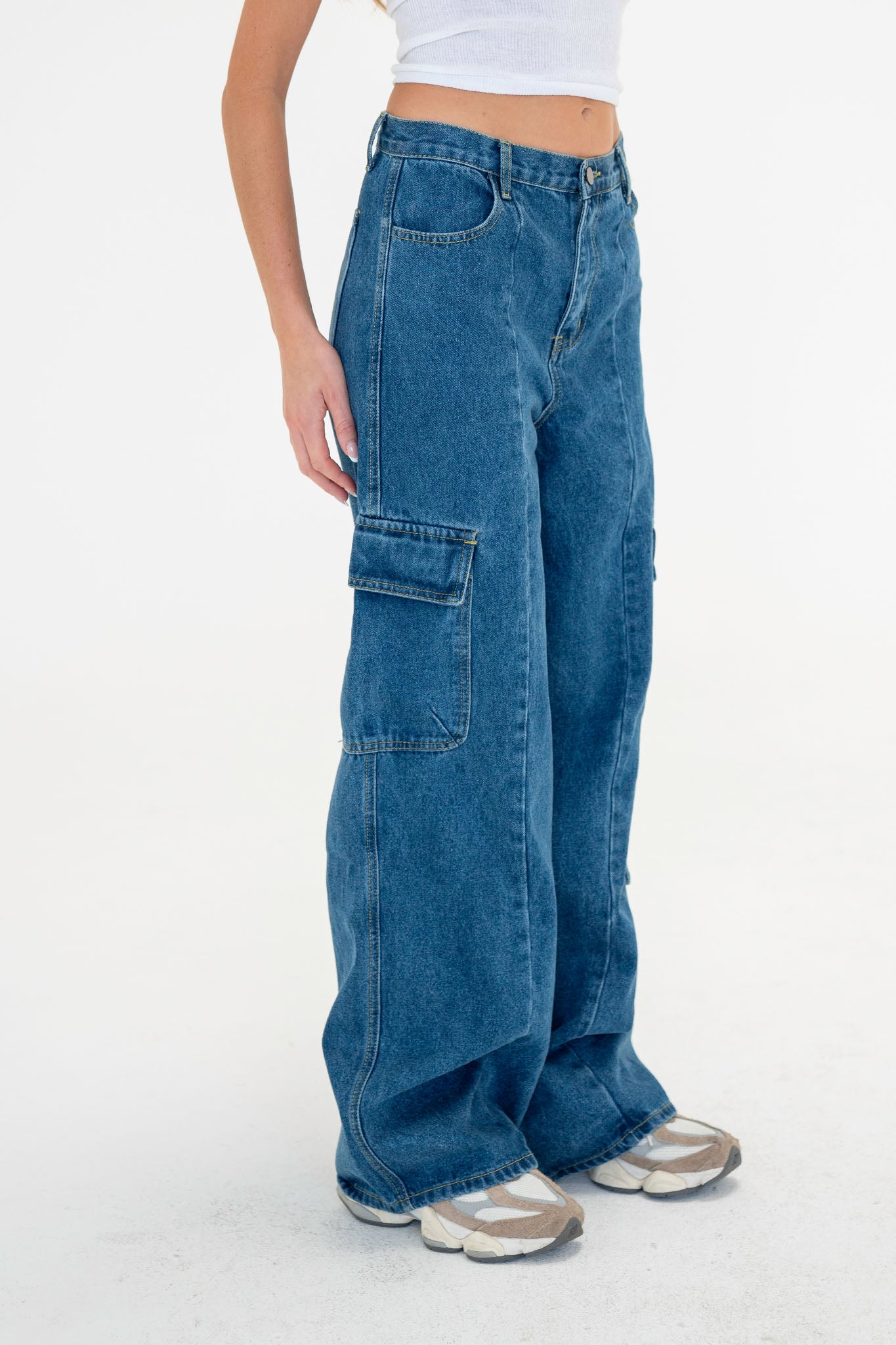 Alt text: Wide leg cargo denim pants in a stylish design, featuring large cargo pockets, a zip fly, and button closure. The model, standing at 5'8" and wearing a size Medium, showcases the pants’ relaxed fit, made from 100% cotton denim.