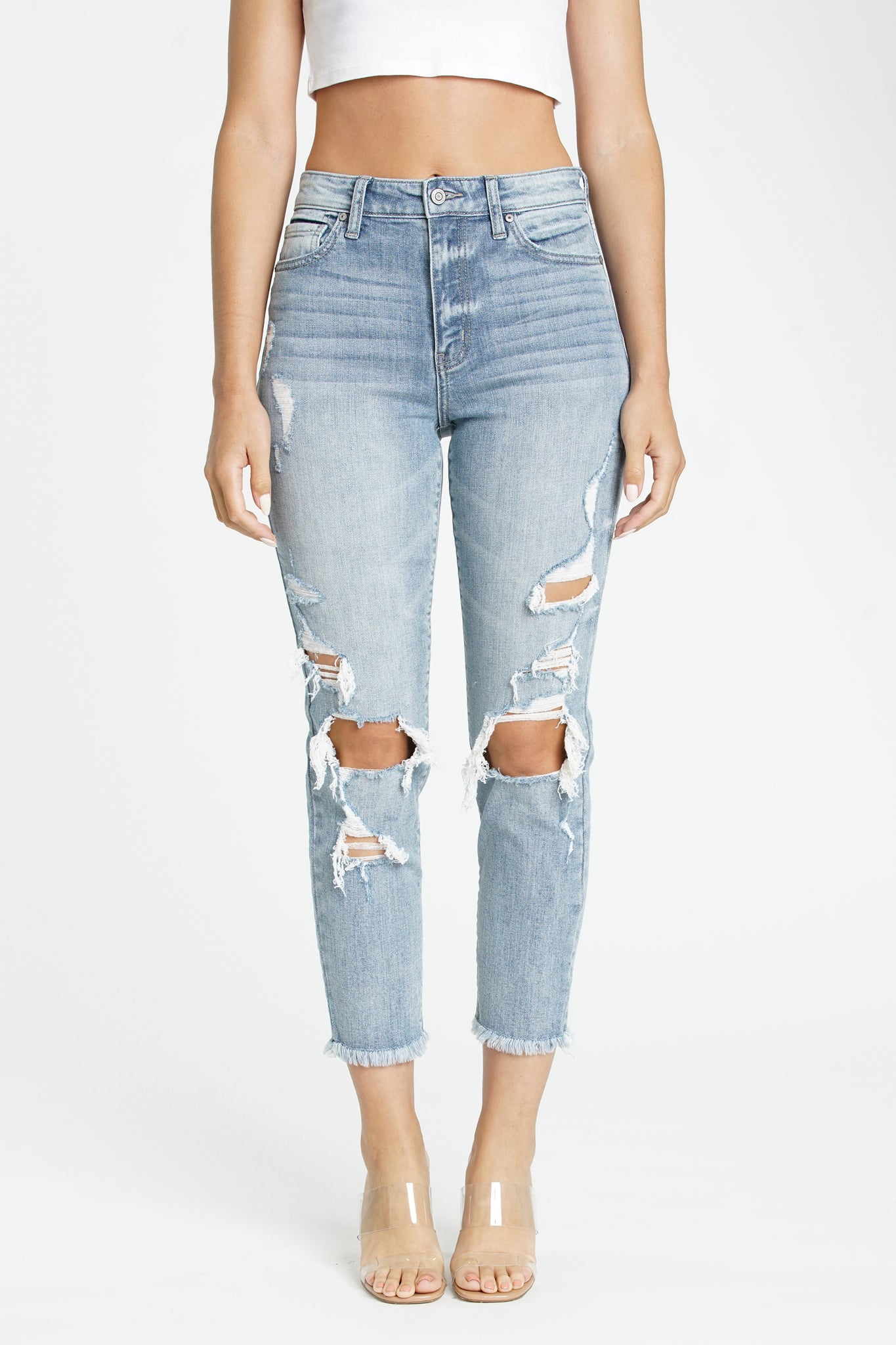 A pair of Eunina Tobi super high rise mom jeans in Cardon, featuring intentionally destroyed knee details and a raw cut frayed hem. The jeans have a faded blue color, a five-pocket design, belt loops, and a hidden zip fly with button closure. The fit includes an 11-inch super-high rise and a 28.5-inch inseam. The material composition is 99% cotton and 1% spandex.