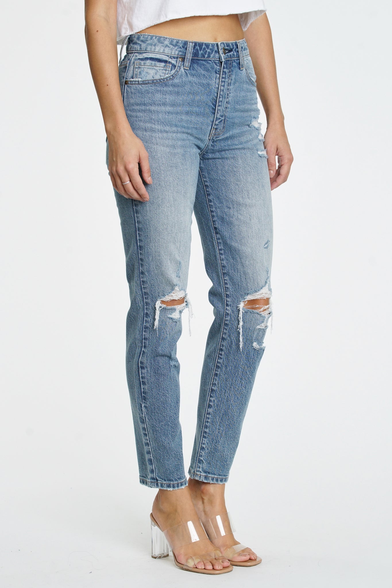 A pair of Eunina Tobi Mom Jeans in a light Whipple wash, featuring a relaxed fit and high waist design. The jeans are styled with subtle distressing and a classic five-pocket layout. Accompanying the jeans are a pair of trendy sunglasses. The image emphasizes the denim's soft texture and contemporary style.