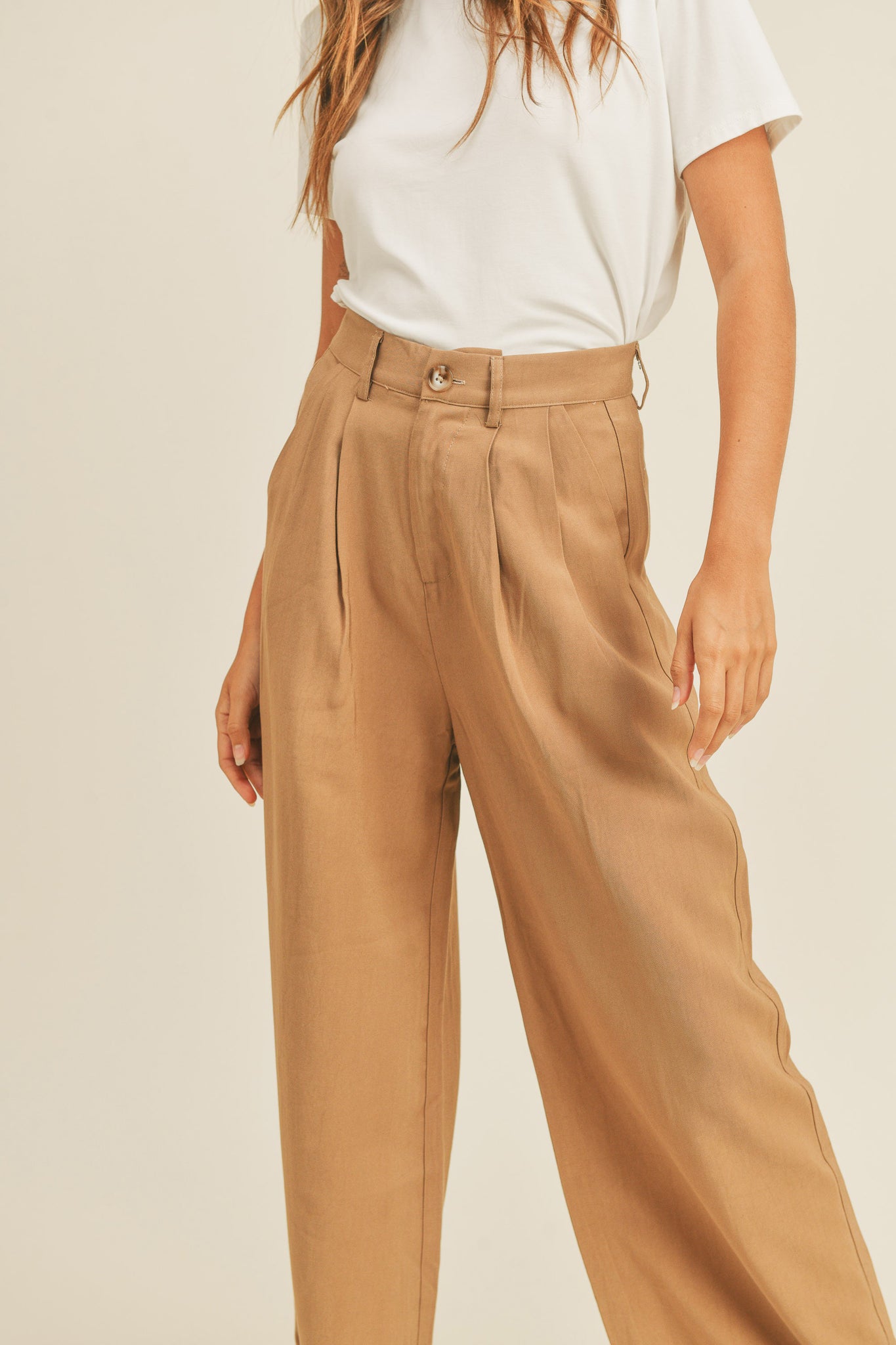Arid Trousers in Camel by Larrea Cove, featuring a stylish design suitable for various occasions. The pants are displayed alongside sunglasses, emphasizing their fashionable appeal. Ideal for the fall season, these trousers are part of the new product line launched in October 2022, currently on sale.