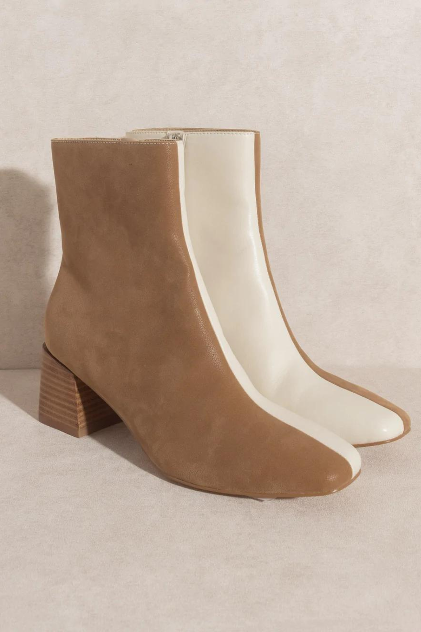 Oasis Society Georgia Dual Chroma Bootie featuring contrasting neutral panels and a slightly flared heel, designed as a stylish statement piece. The bootie has a 5.75-inch shaft height, a 2.25-inch heel height, a leather-wrapped heel, and a padded insole. The closure type is a zipper, with an opening circumference of 11 inches and a sole length of 5 inches.