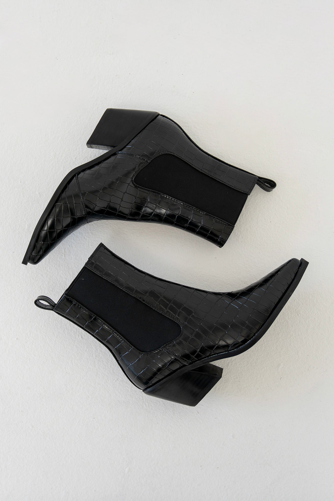 Billini Ukaya Bootie in a sleek monochrome design, featuring a modern silhouette. The bootie is showcased alongside stylish sunglasses, highlighting a trendy footwear and accessory combination. Available for sale as a new product from 2022.