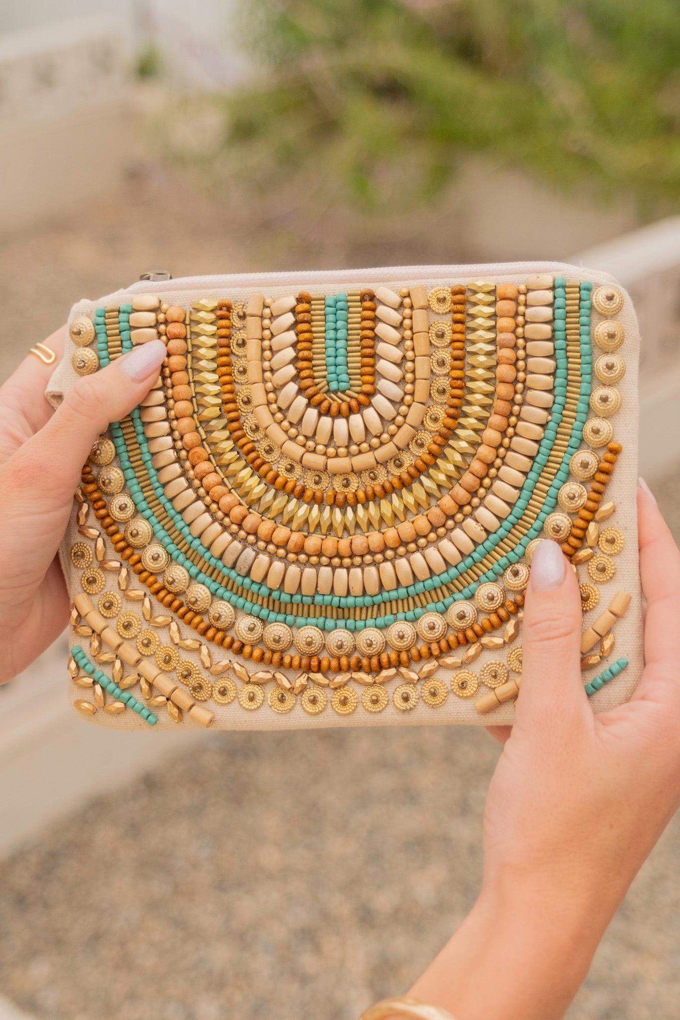 A vibrant turquoise Allegra Beaded Wristlet by ANTIK KRAFT, featuring intricate beadwork, a lined interior, and a compact design measuring 8" x 6". The wristlet is showcased against a neutral background, emphasizing its boho beachy chic style, perfect for carrying small essentials.