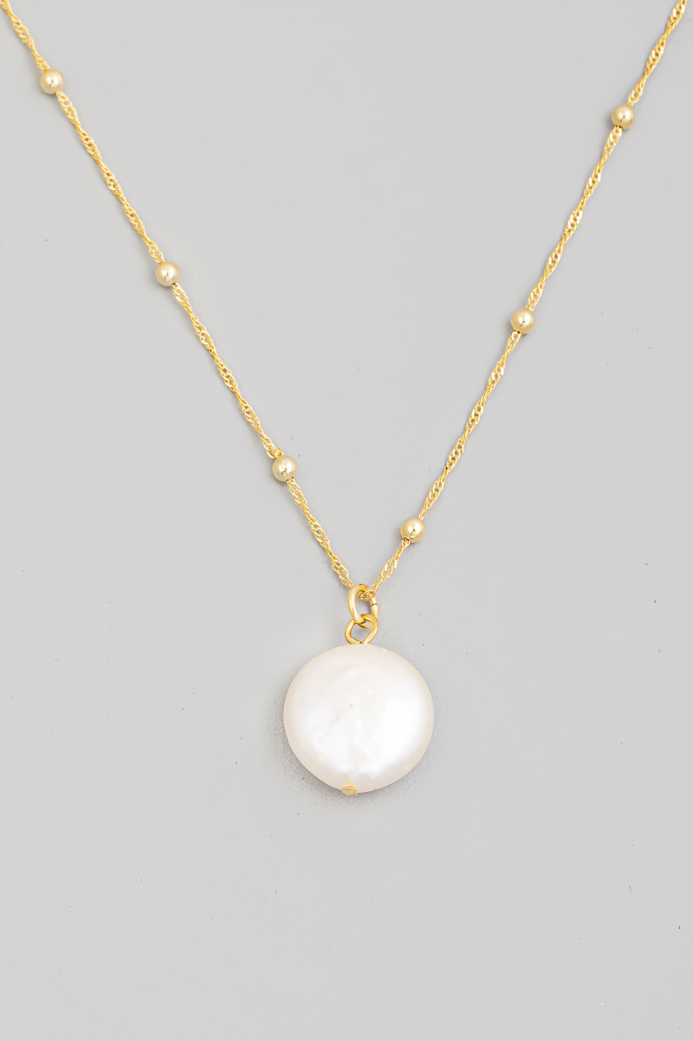 A stylish Woods Cove Pearl Charm Necklace by Larrea Cove featuring a delicate design with pearl accents. The necklace is showcased against a neutral background, highlighting its elegance and simplicity. Ideal for layering or wearing alone, it embodies the essence of contemporary jewelry.