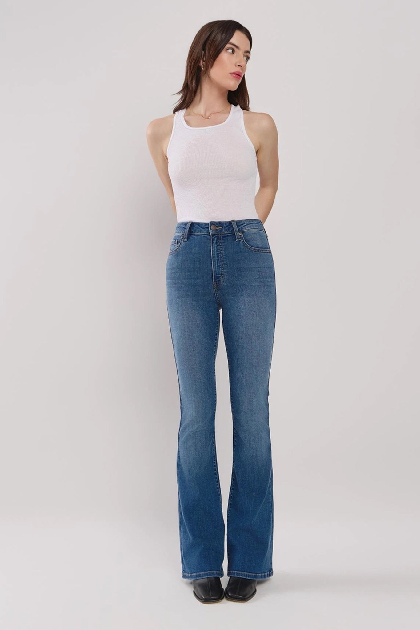 A pair of high-rise flare jeans in the Gilia wash by Eunina, featuring a stylish flare at the bottom. The jeans are paired with trendy sunglasses. The overall look is modern and casual, suitable for everyday wear.