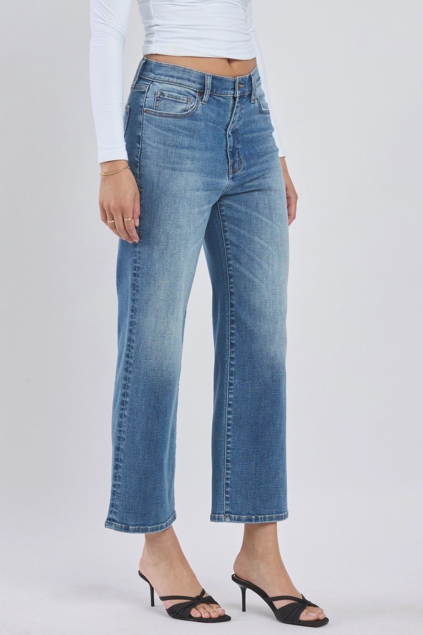 A pair of Eunina Dawn Wide Leg Jeans in a light blue wash, featuring a high waist and relaxed wide leg silhouette. The jeans are displayed on a flat surface with a pair of stylish sunglasses placed next to them. The overall look is casual and trendy, suited for summer fashion.