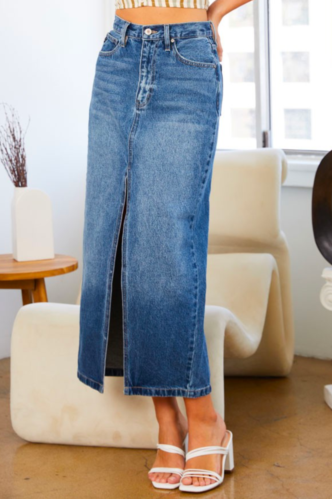 A KanCan 90s denim maxi skirt, featuring a classic high-waisted design and a long, flowing silhouette. The skirt is styled with a casual, vintage aesthetic, perfect for fall fashion. It is displayed against a neutral background, highlighting its denim texture. Accompanying the skirt are trendy sunglasses, adding a stylish touch to the outfit.