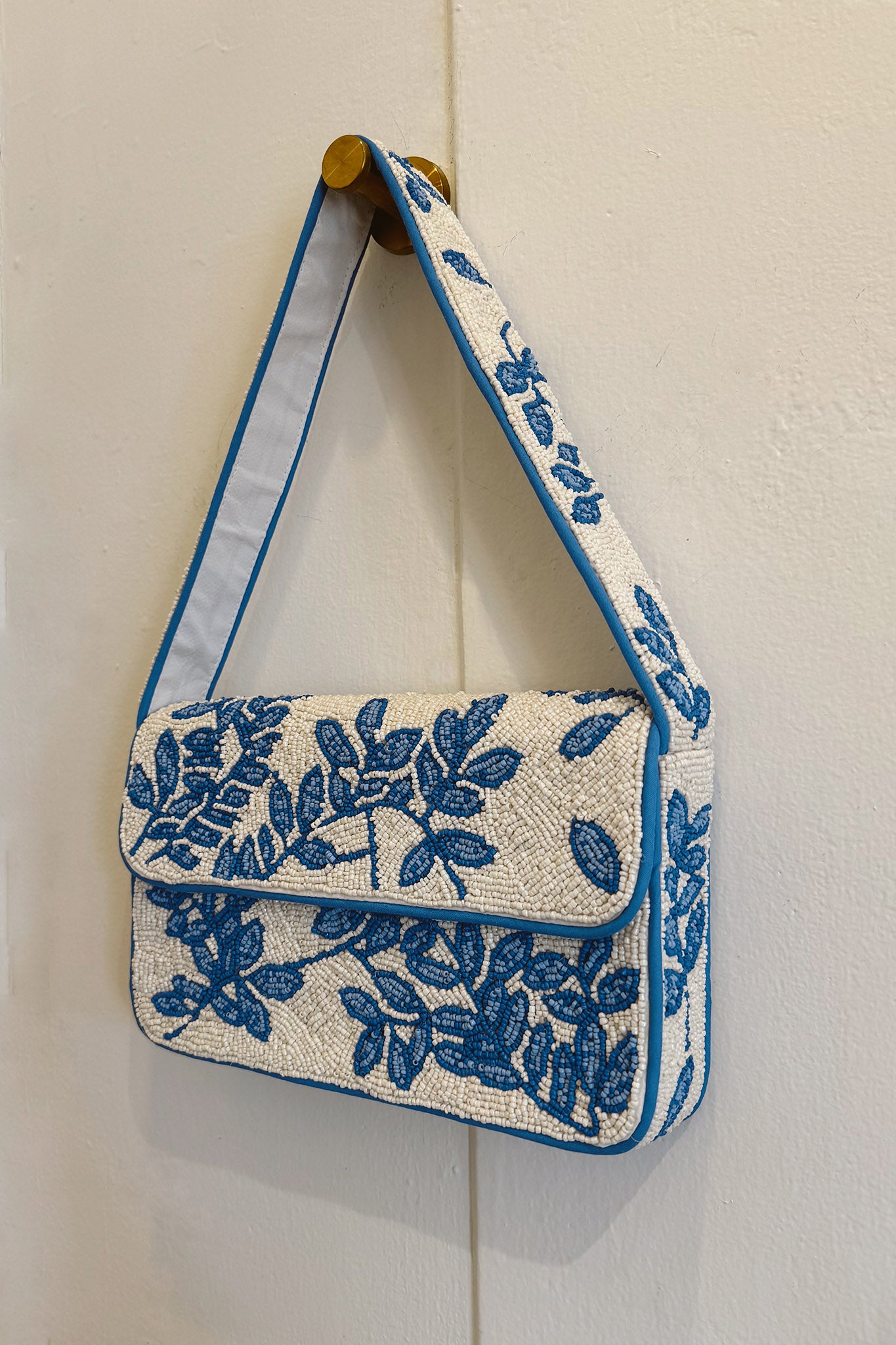 Lagunita Hand Beaded Shoulder Bag in blue by ANTIK KRAFT, featuring intricate hand-beaded designs. The bag is displayed alongside stylish sunglasses, highlighting its summer appeal. Ideal for the 2024 collection.