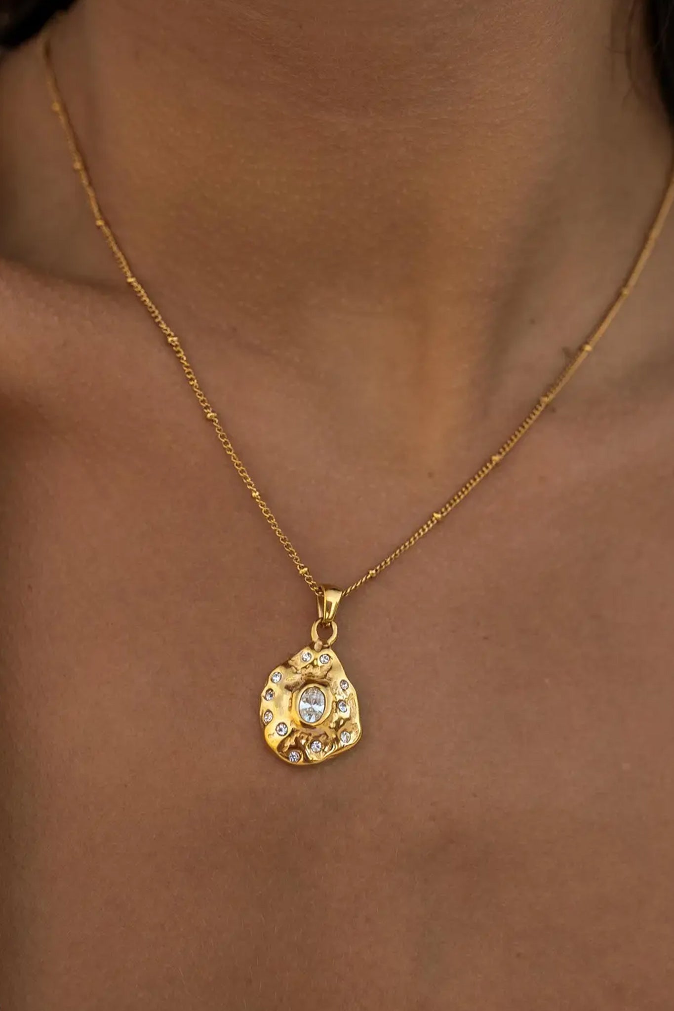 Luna Amulet necklace featuring an 18K gold-plated design with stainless steel, adorned with cubic zirconia stones and a shell coating. The necklace is hypoallergenic, nickel and lead-free, and includes a lobster clasp, with a 16-inch chain and 2-inch extender. It is water-resistant.