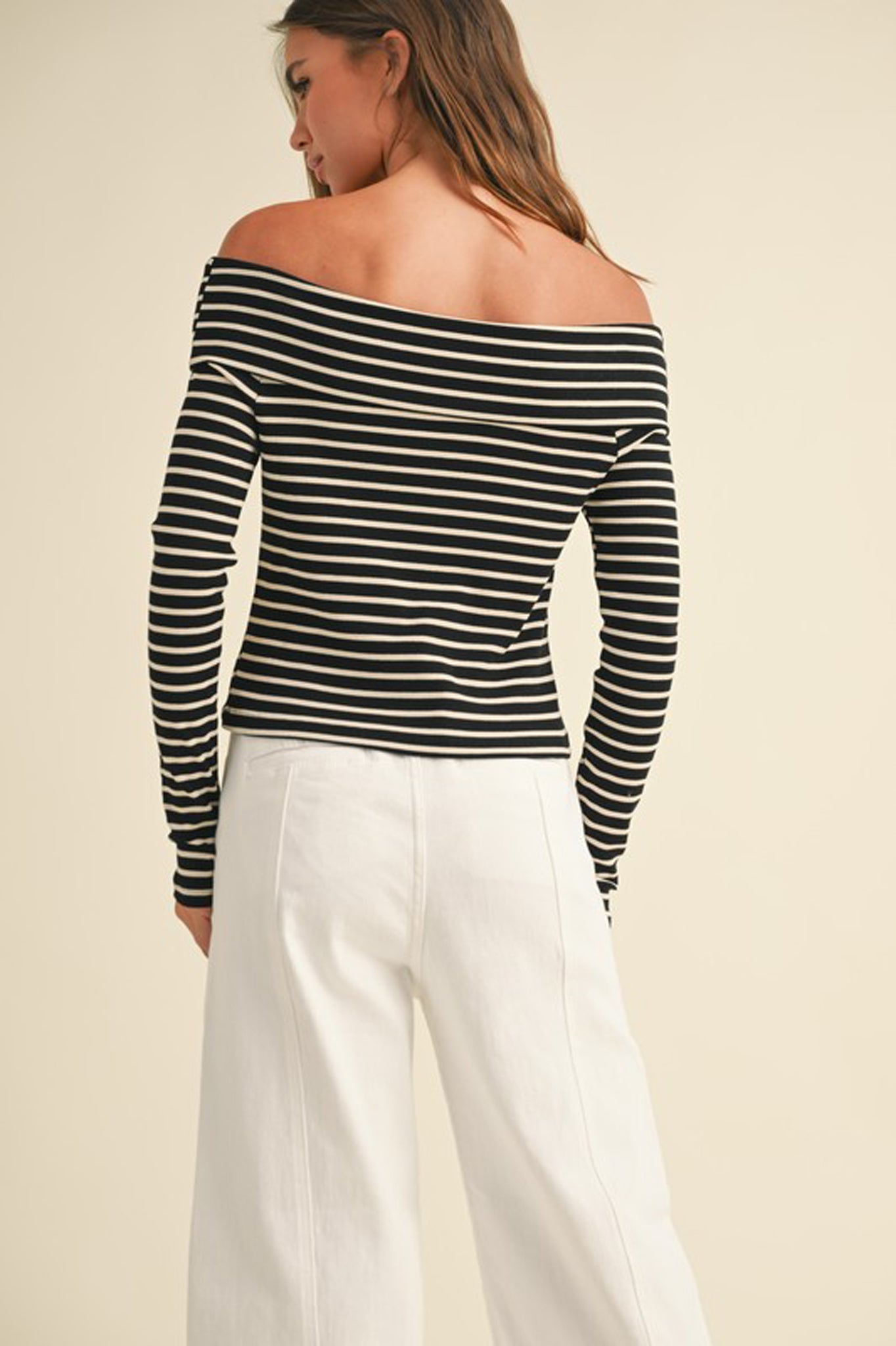 A ribbed long-sleeve off-the-shoulder top in a soft fabric, designed by Larrea Cove. The top features fitted sleeves and a stylish neckline, making it suitable for fall fashion. The model is accessorized with trendy sunglasses, enhancing the chic look. The image conveys a contemporary style perfect for the Fall 2024 season.