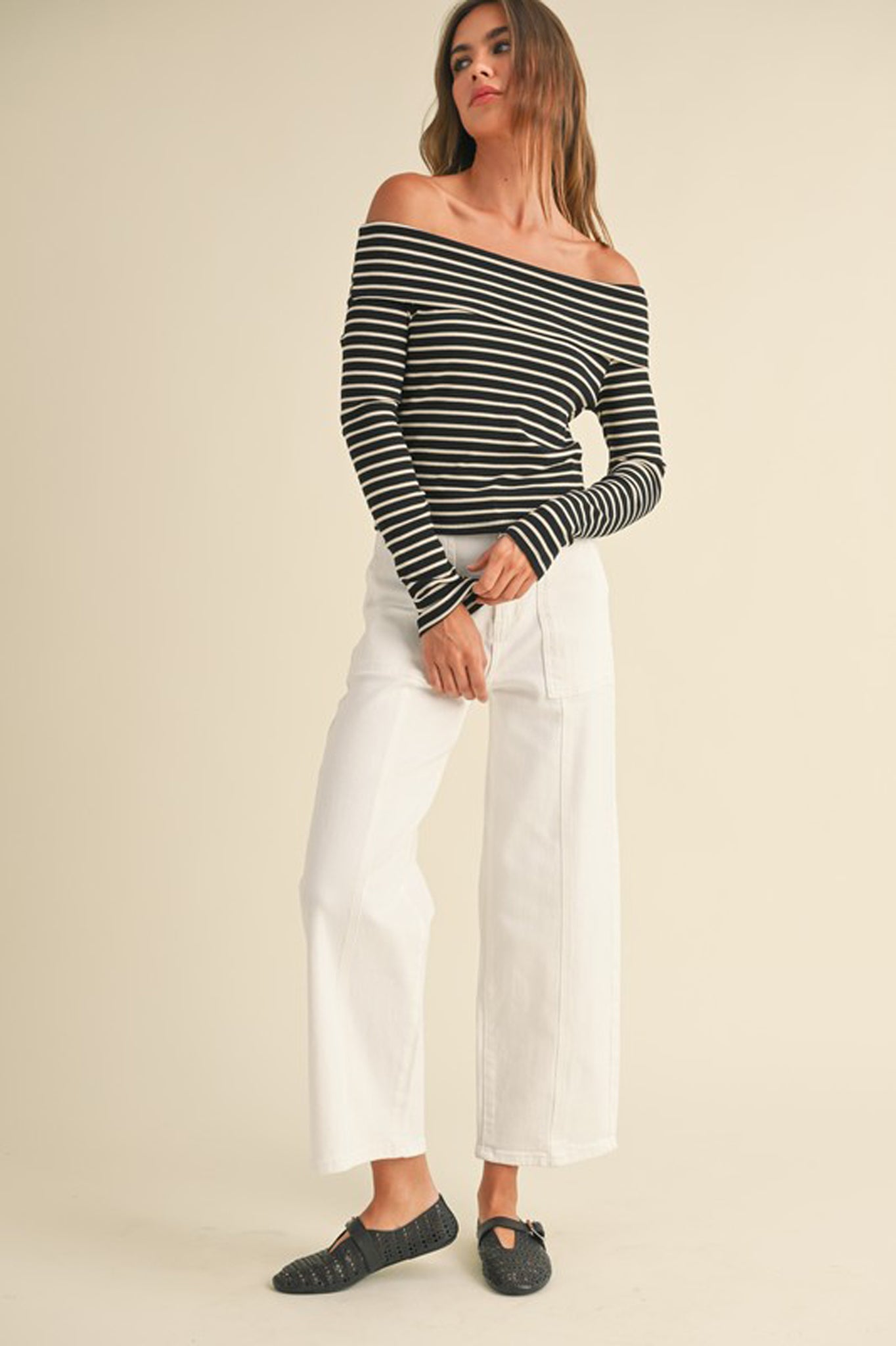 A ribbed long-sleeve off-the-shoulder top in a soft fabric, designed by Larrea Cove. The top features a fitted silhouette and elegant neckline, perfect for a stylish fall look. Paired with trendy sunglasses, it showcases a chic and fashionable outfit suitable for the Fall 2024 season.