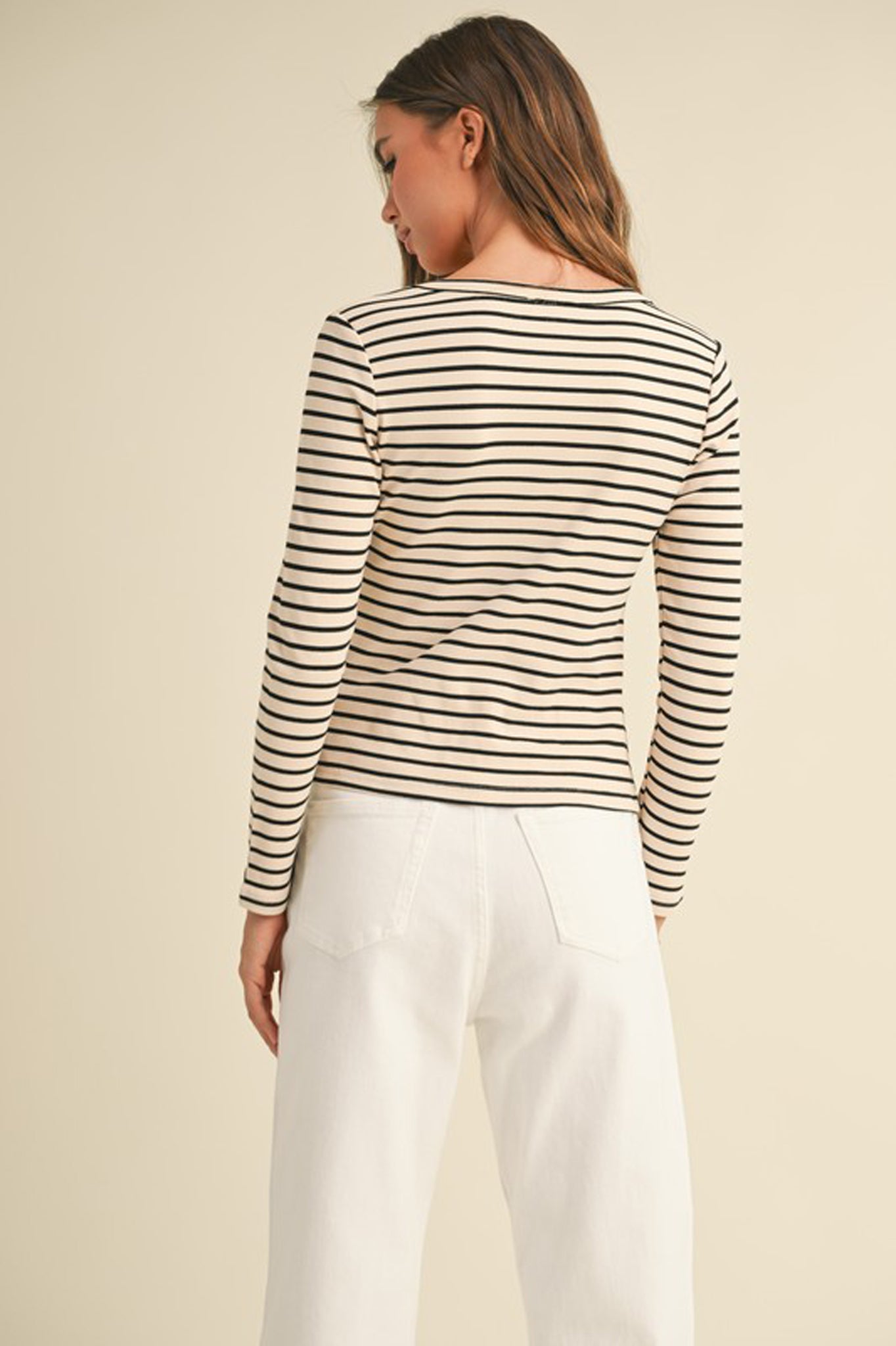 A ribbed long-sleeve scoop-neck top in a soft fabric, designed by Larrea Cove. The top features a fitted silhouette, ideal for layering in the Fall 2024 season. The color is a warm neutral tone, perfect for autumn styles. Accompanying the top are stylish sunglasses, adding a chic touch to the outfit.