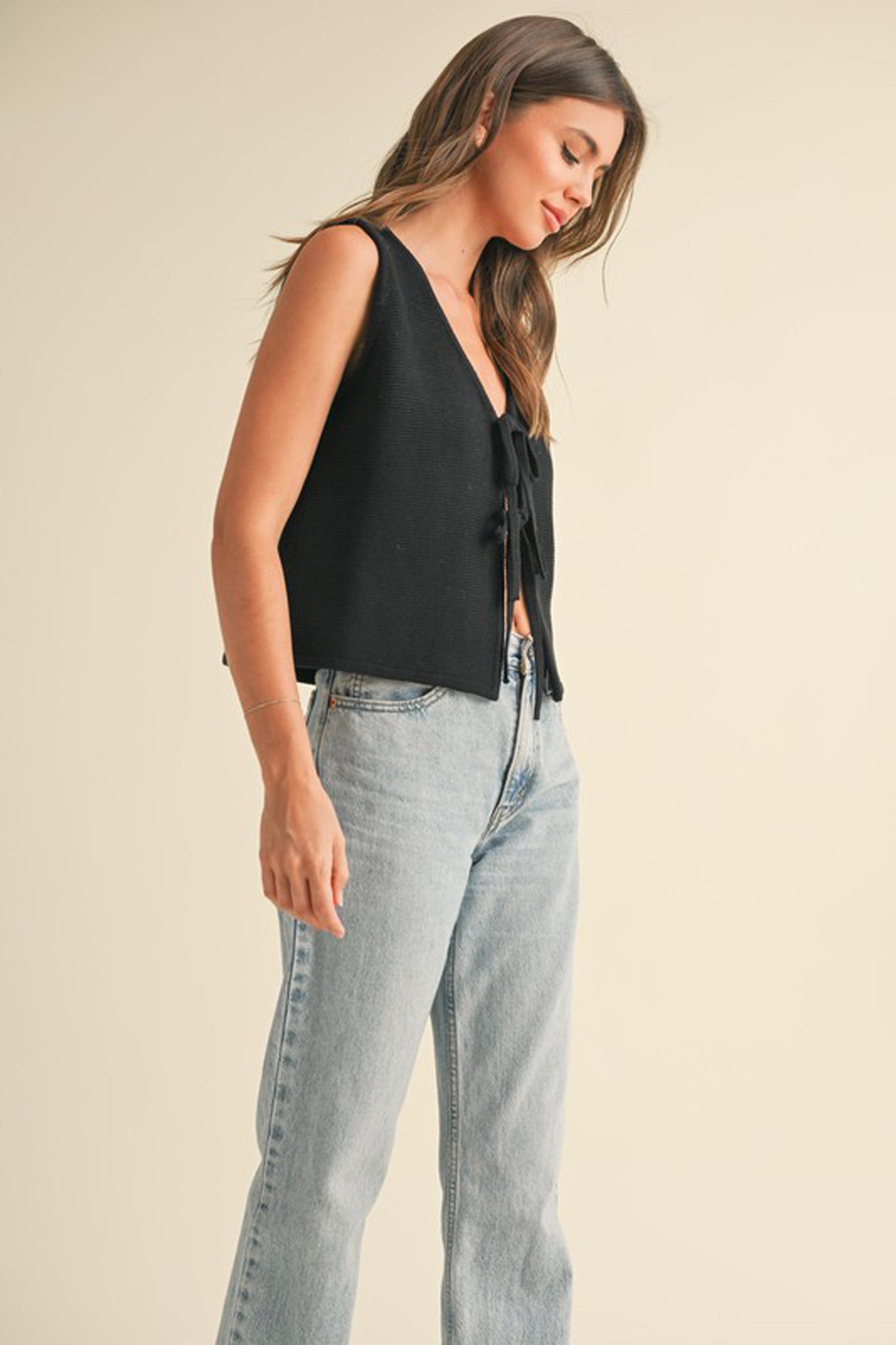 A stylish tie front knit vest top by Larrea Cove, featuring a relaxed fit and a modern design, ideal for fall fashion. The top is paired with fashionable sunglasses, enhancing its chic appeal.